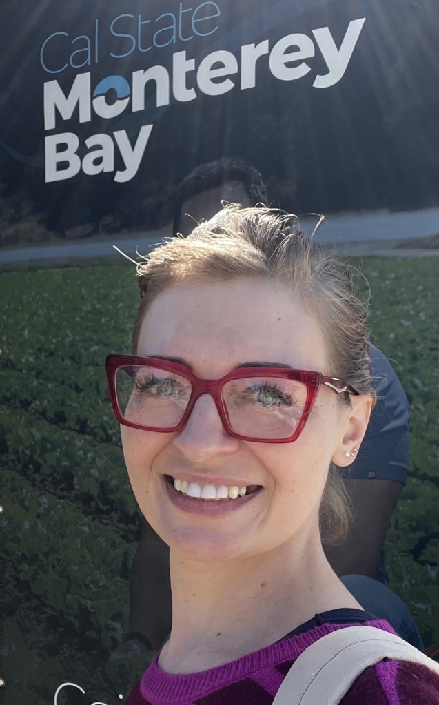 Sara Rose at CSUMB in front of a banner. Orientation weekend, August 2024. 